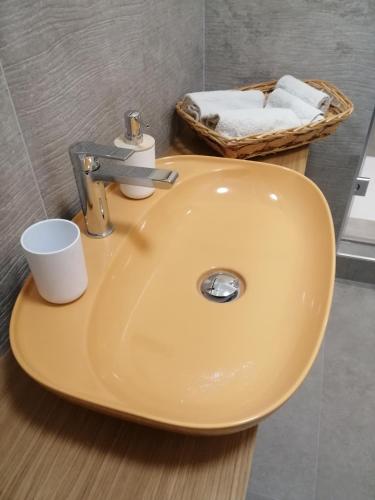 a yellow sink in a bathroom with a basket of towels at Residenza Albula Perusia in Perugia