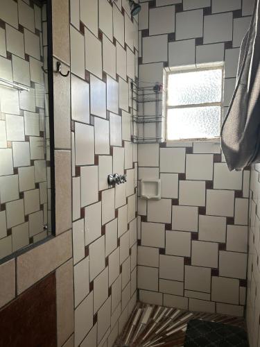 a shower with white tiled walls and a window at Sweet Dream Overnight 2 in Postmasburg