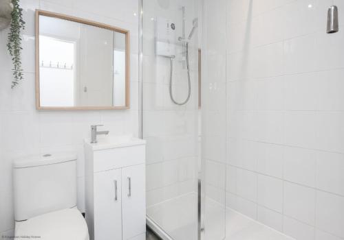 een witte badkamer met douche en wastafel bij Chalet Eighteen in Deal