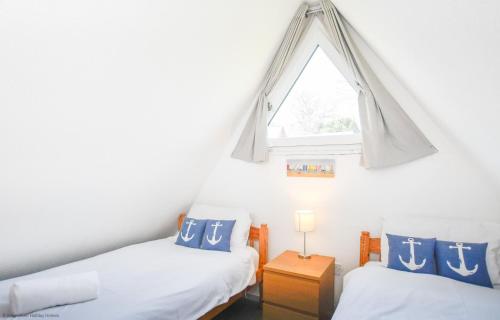 twee eenpersoonsbedden in een kamer met een raam bij Chalet Eighteen in Deal