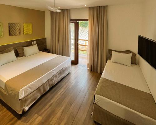 Un dormitorio con dos camas y una ventana. en Ravenala Hotel, en Arraial d'Ajuda