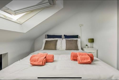 Una cama blanca con dos almohadas naranjas. en The Little Oaks, en Birmingham