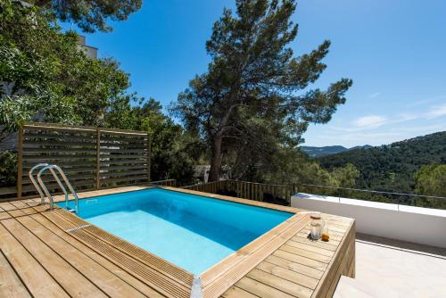 a swimming pool with a wooden deck and a swimming poolvisor at Casa Zita Verde - Ibiza style villa with sea view & sunset BBQ in Cala Llonga