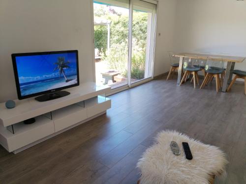 un salon avec une télévision et une table avec des chaises dans l'établissement Maison avec Jardin proche du tram, à Le Crès