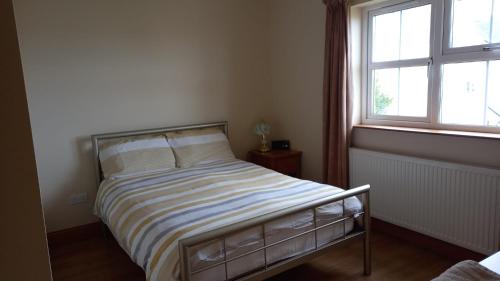 a bedroom with a bed with a striped blanket and a window at Dungloe House in Dungloe