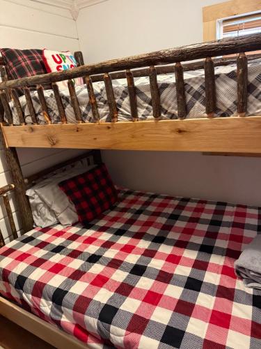 a bunk bed with a checkered blanket on it at The Cabins at Walnut Grove-minutes from Hunter and Windham in Ashland