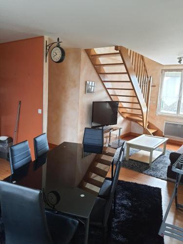un salon avec une table et des chaises et un escalier dans l'établissement L'escapade, à Carolles