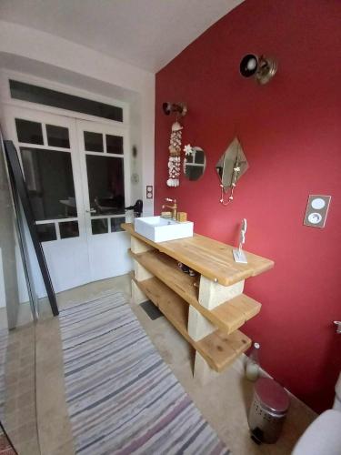 La salle de bains est pourvue d'un lavabo et d'un mur rouge. dans l'établissement Maison chaleureuse, à Saint-Quentin-la-Poterie