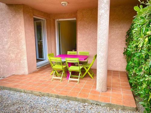 une terrasse avec une table rose et des chaises vertes dans l'établissement Pour 4 personnes, 15 minutes à pied de la plage, à Saint-Cyprien