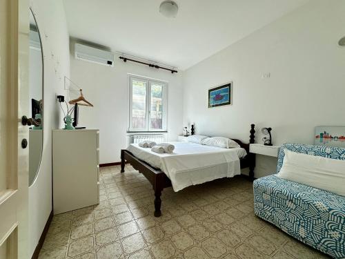a white bedroom with a bed and a chair at Terrace & Parking - Holiday Home near Fegina Beach in Monterosso al Mare