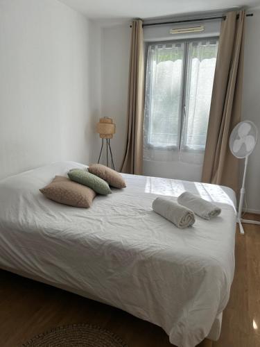 une chambre avec un lit avec des oreillers et une fenêtre dans l'établissement Charmant 2P Cosy Bord de Seine avec terrasse, à Mantes-la-Jolie