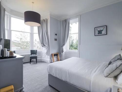 a white bedroom with a bed and a desk and window at McInnes House rooms with breakfast in Kingussie