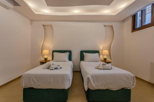 two beds in a room with white walls at Kallisti Beach & Spa Villa - A Luxury Seaside Retreat in Lachi