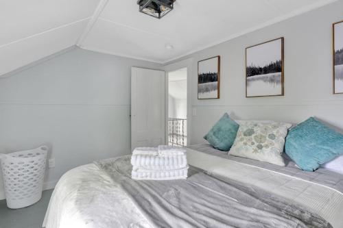 a white bedroom with a large bed with blue pillows at Spacious Lakeside Retreat 4-Bedroom Game Room in Orono