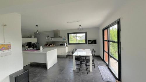 - une cuisine avec des comptoirs blancs et une table avec des chaises dans l'établissement Le confort contemporain dans un écrin de verdure, à Vernon