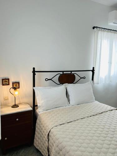 a bedroom with a bed with white sheets and a window at Chaido Studios in Plaka Milou