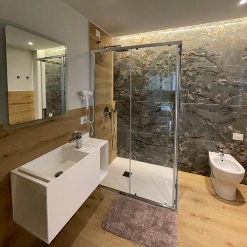 a bathroom with a glass shower and a sink at Atlantide Suites Tropea in Tropea