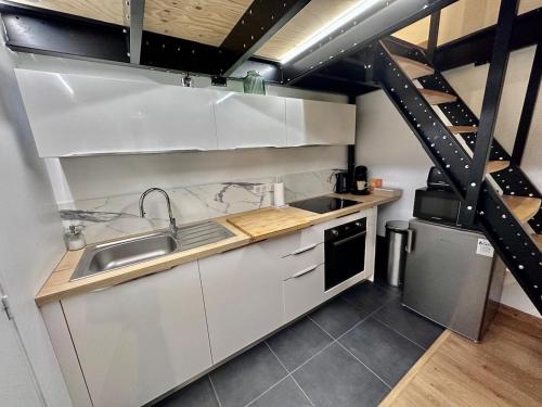 une petite cuisine avec un évier et une cuisinière dans l'établissement Douce Parenthèse, à Roanne