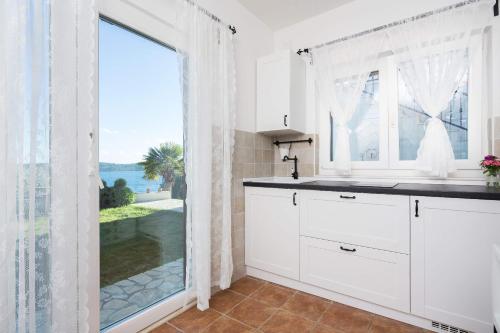 a kitchen with white cabinets and a large window at Apartments Panorama 2 in Trogir