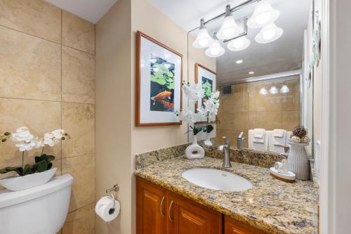 Un baño con lavabo, inodoro y espejo. en Mahana 913, en Kahana