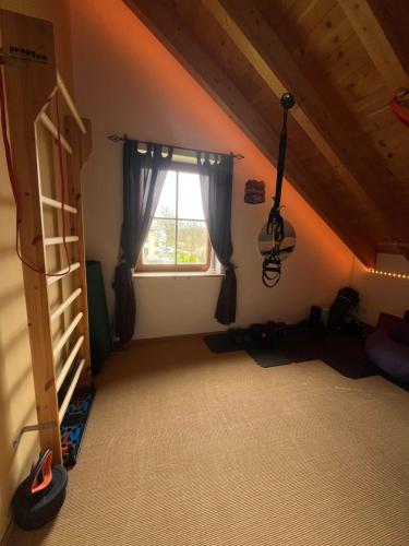 a attic room with a ladder and a window at La Dolce Vita im Tiroler-Holzhaus in Bad Elster