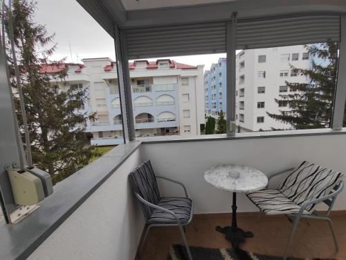 a balcony with a table and two chairs and windows at Banja Koviljaca Centar Apartman in Banja Koviljača