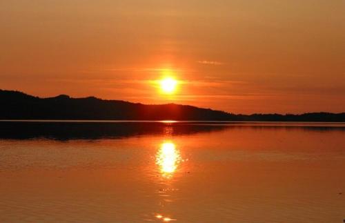 a sunset over a large body of water at Lofoten MidnightSun Lodge in Sandsletta