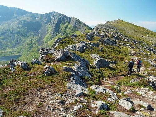 two people walking on a rocky mountain at Lofoten MidnightSun Lodge in Sandsletta