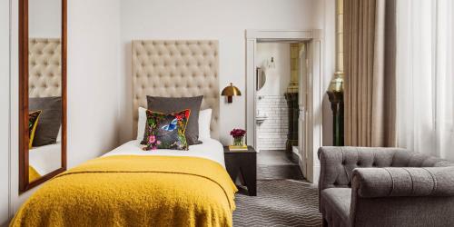 a bedroom with a bed with a yellow blanket and a chair at Kimpton Clocktower by IHG in Manchester