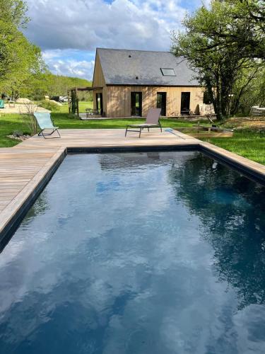 une piscine avec deux chaises et une maison dans l'établissement Les Caminols, à La Dornac