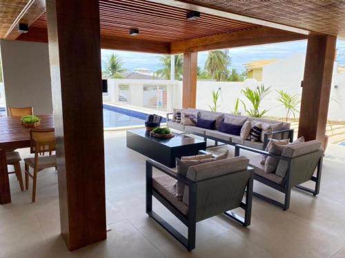 un salon avec un canapé et des chaises et une piscine dans l'établissement Casa Praiana Litoral, à Camaçari