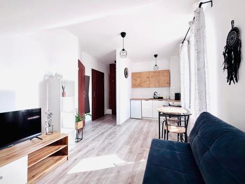 Una sala de estar con un sofá azul y una cocina. en Apartament Salton, en Bochnia