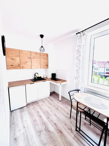 cocina con armarios blancos, mesa y ventana en Apartament Salton, en Bochnia