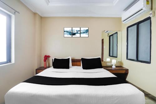 a bedroom with a large bed and two windows at Super Hotel O Pithampur Formerly Ganga Residency in Akolia