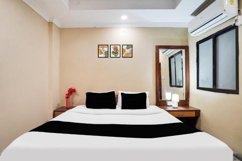 a bedroom with a large white bed with black pillows at Super Hotel O Pithampur Formerly Ganga Residency in Akolia