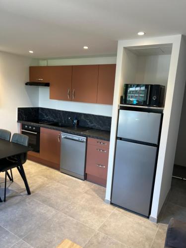 une cuisine avec un réfrigérateur et un micro-ondes dans l'établissement Appartement T2, neuf, climatisé avec terrrasse, à Aix-les-Bains