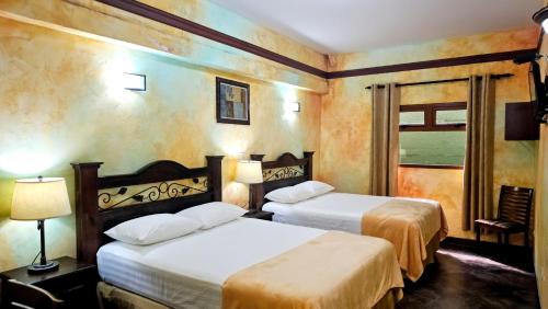a hotel room with two beds and a window at Antigua Inn Hotel in Guatemala