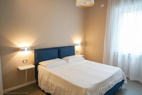 a bedroom with a bed with a blue headboard and a window at Onda del Mare in Mazzeo