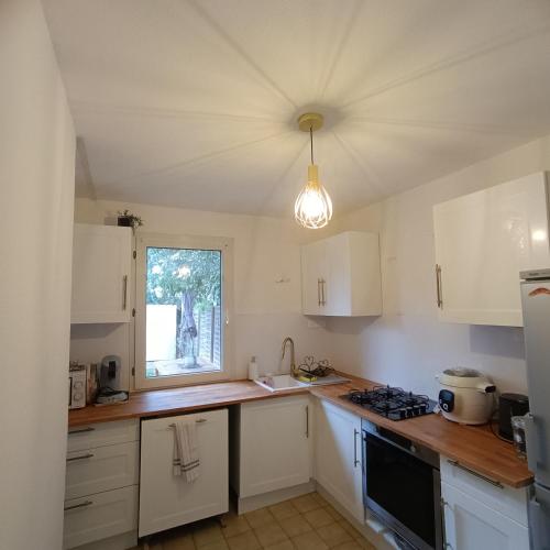 une cuisine avec des armoires blanches et une fenêtre dans l'établissement Villa Mont D'Or, à Manosque