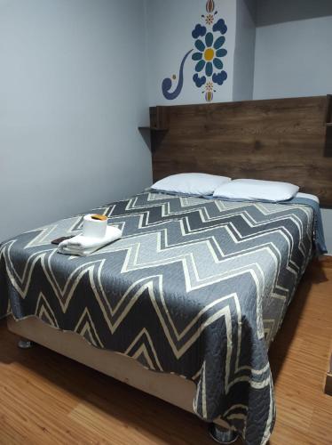 a bed with a black and white comforter in a room at HOTEL CASA RUSTICA Jr CALLAO 264 HUAMANGA AYACUCHO in Ayacucho