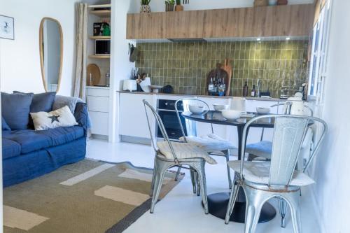 une cuisine avec une table, des chaises et un canapé bleu dans l'établissement Ti TITE- jardin clos - plage à pieds, à Crozon