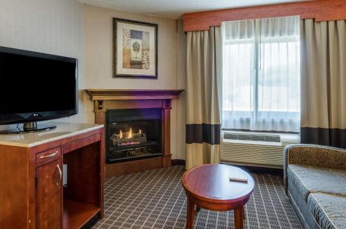 a living room with a television and a fireplace at Comfort Inn & Suites West Springfield in West Springfield