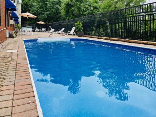 a blue swimming pool with chairs and umbrellas at Comfort Inn & Suites Sturbridge-Brimfield in Sturbridge