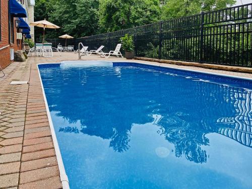 a blue swimming pool with chairs and umbrellas at Comfort Inn & Suites Sturbridge-Brimfield in Sturbridge