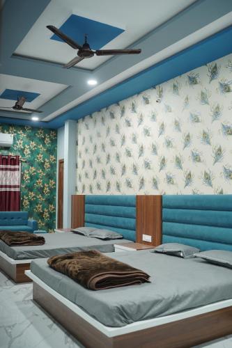 a bedroom with two beds and a ceiling fan at Hotel Shree Radhe Krishna in Ujjain