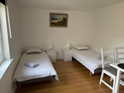 two beds in a room with white walls and wooden floors at Country Lodge Lärkboet in Laholm