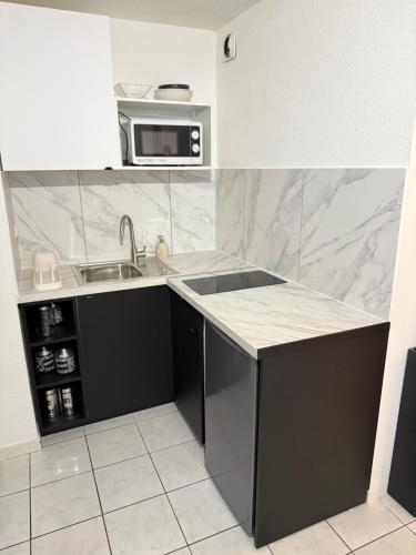 une cuisine avec un évier et un micro-ondes dans l'établissement Appartement Quai de Bosc, à Sète