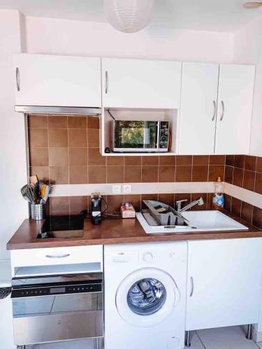 une cuisine avec un évier et une machine à laver dans l'établissement Apartment 2 steps from Bergerie Beach!, à Hyères