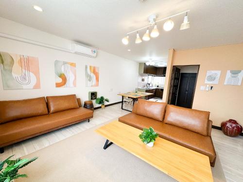 a living room with brown leather couches and a table at MATSUNE 松寧 6min walk to Noboribetsu st in Noboribetsu