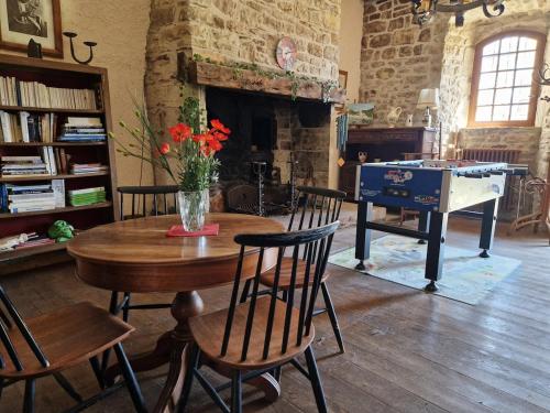 Cette chambre comprend une table avec des chaises et un piano. dans l'établissement Gite de Montrepos - Ancien Presbytère XVIIe siècle, à Estaing